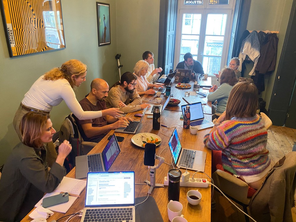 Group vibe coding session at a long table in Lisbon